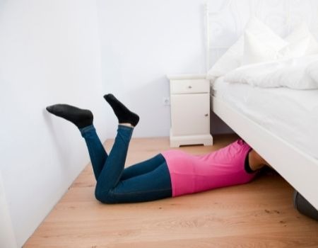 woman cleaning under bed