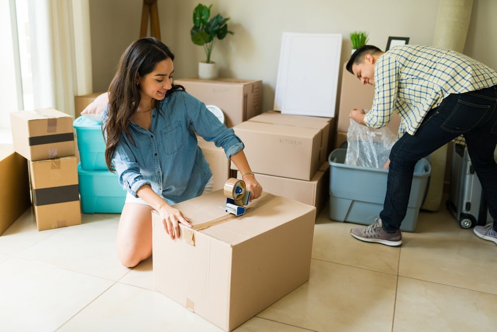 couple packing and taping boxes while combining households