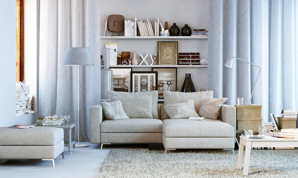 living space with cream couch and clutter/stuff on tables and bookshelves